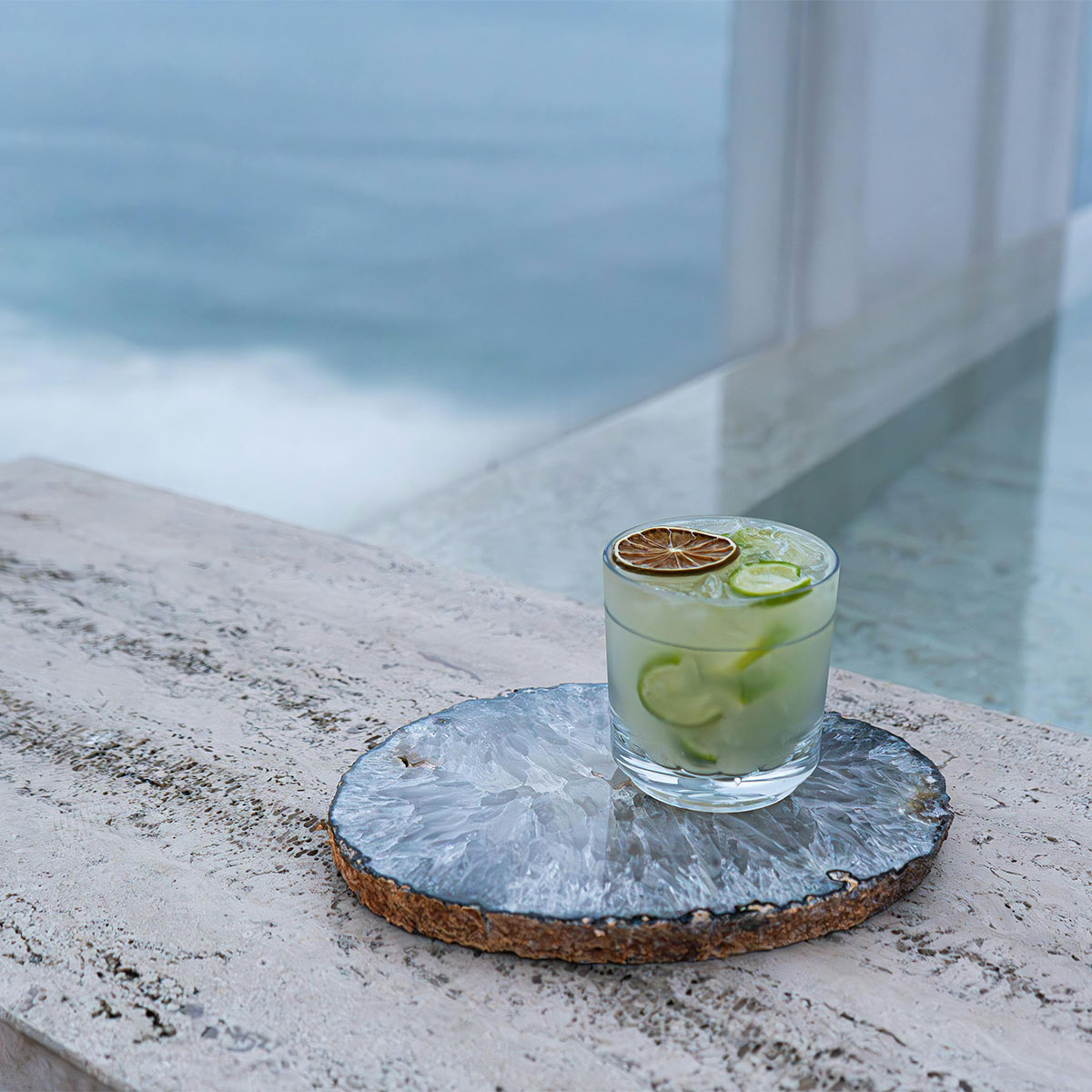 Cocktail on marble tray beside the pool — refined and minimal tropical luxury.