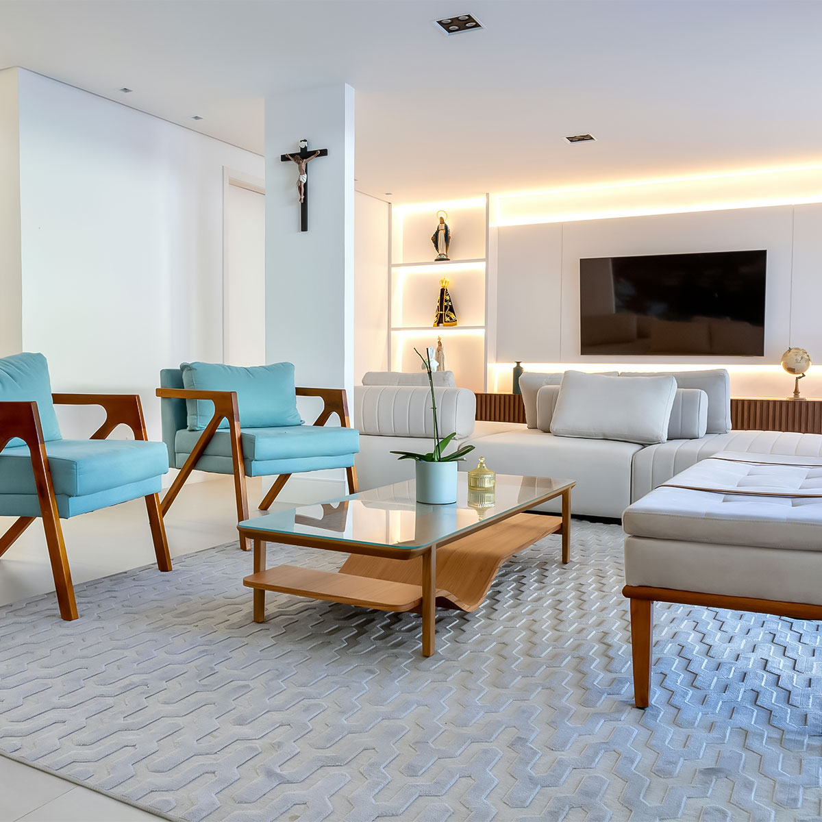 Warm and contemporary living room at Casa Amorsol featuring soft neutral tones, ocean-inspired blue armchairs, and elegant ambient lighting that create a calm seaside atmosphere.