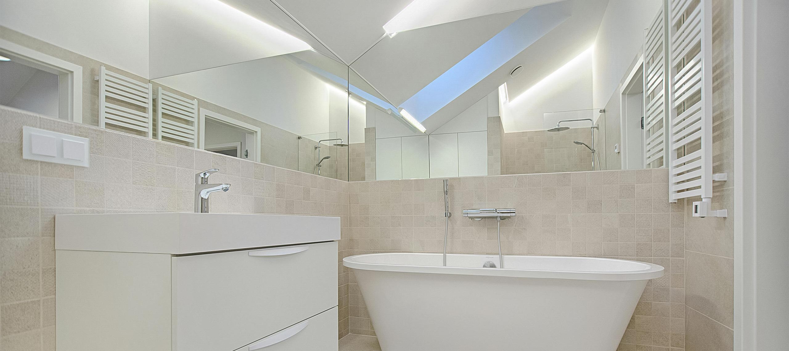 Elegant villa bathroom with freestanding white tub, neutral tiles, modern vanity, and skylight — bright, minimalist design for a serene coastal experience.