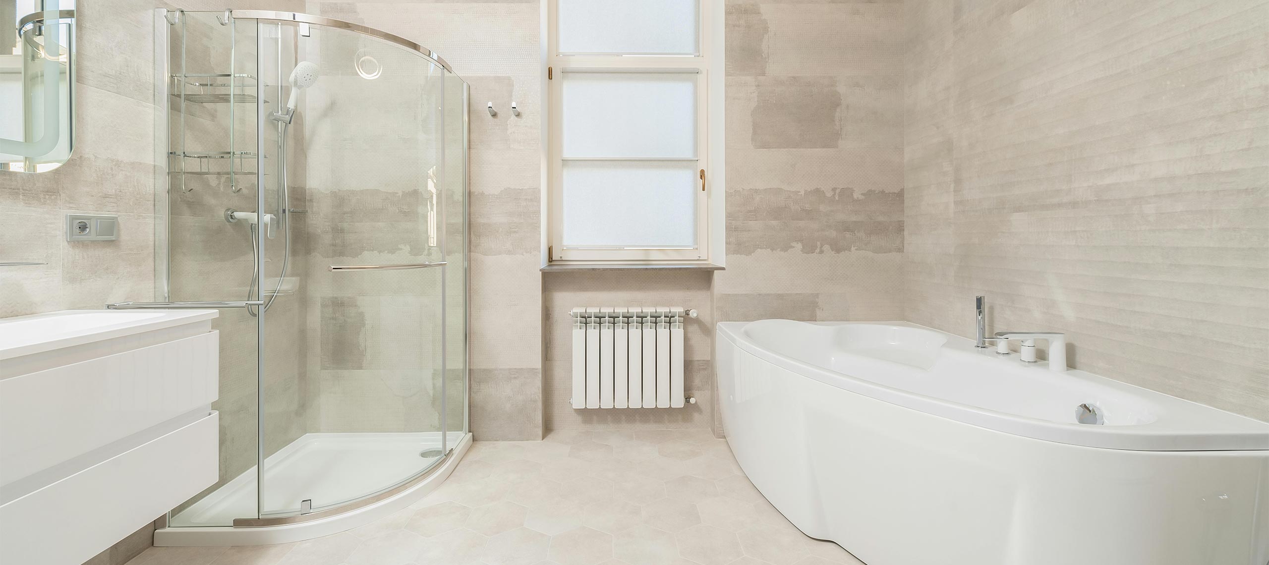 Contemporary villa bathroom with glass walk-in shower, freestanding bathtub, and beige stone walls — a serene, light-filled space designed for comfort and relaxation.