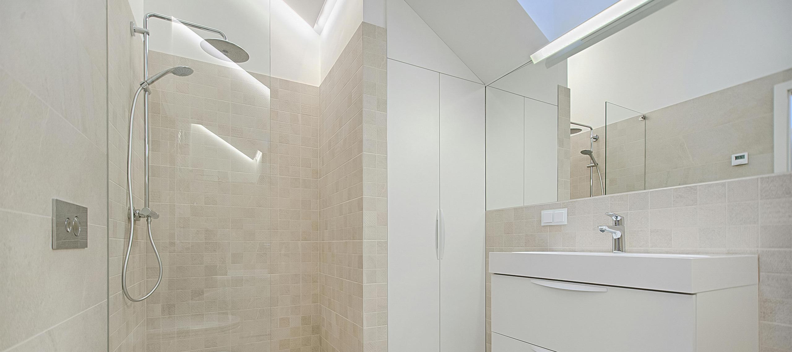 Modern villa bathroom with walk-in rain shower, white vanity, and neutral tiled walls — minimalist, bright, and designed for a relaxing coastal stay.